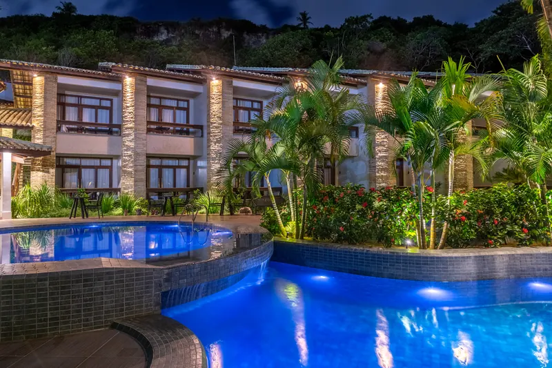 Piscina iluminada à noite em frente às suítes